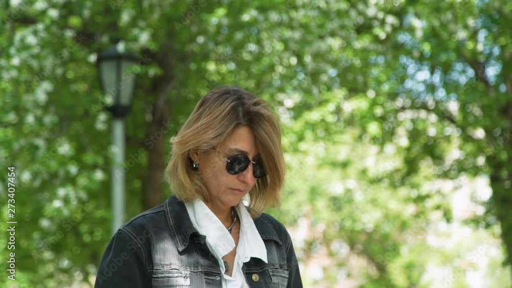 Mature Freelancer Woman Working in a City Park in Sunny Day. Woman Using Laptop for her Work. Freelance Work, Business People Concept Mature Freelancer Woman Working in a City Park in Sunny Day. Woman Using Laptop for her Work. Freelance Work, Business People Concept