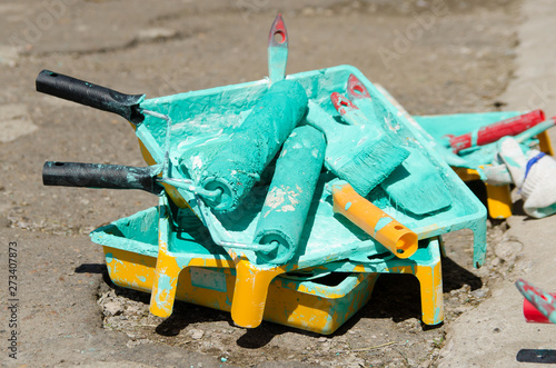 several paint rollers covered with green paint are in the tray