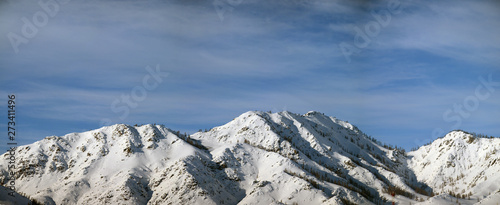 Winter panorama with snow-capped mountains and blue sky