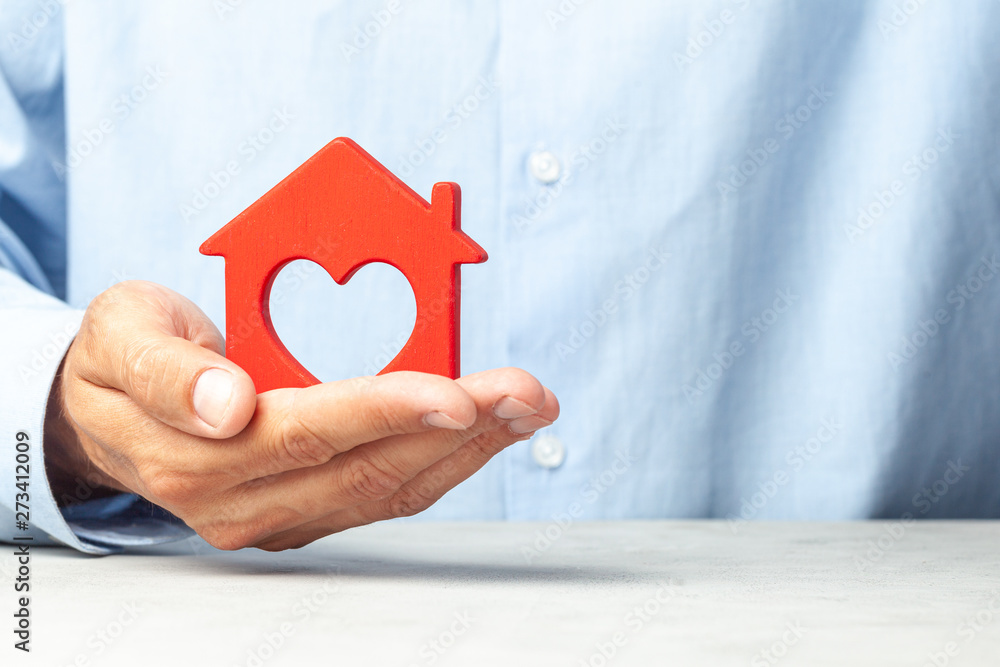 Man in blue shirt holds house in his hands. Concept realtor offers to buy house or real estate loan Man in blue shirt holds house in his hands. Concept realtor offers to buy house or real estate loan