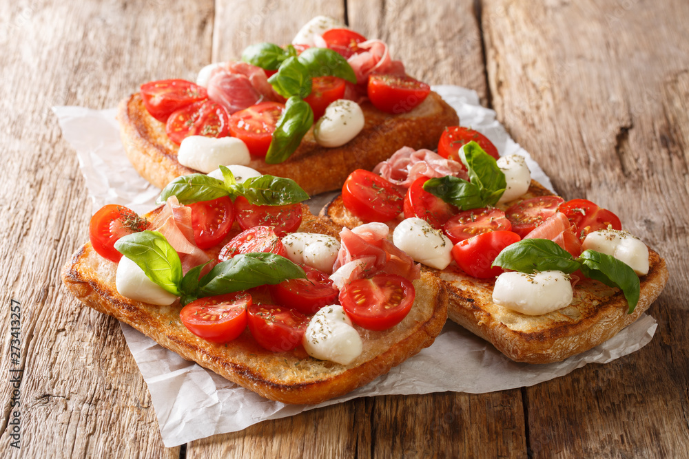 Ciabatta summer toasts with mozzarella, tomatoes, ham and basil close-up on the table. horizontal Ciabatta summer toasts with mozzarella, tomatoes, ham and basil close-up on the table. horizontal