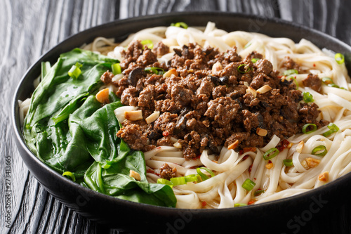 recipe for dan dan noodles with minced meat and greens closeup in a plate. horizontal