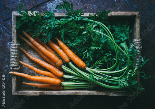 Fototapete Bunch of fresh baby carrots in a wooden box top view space for text