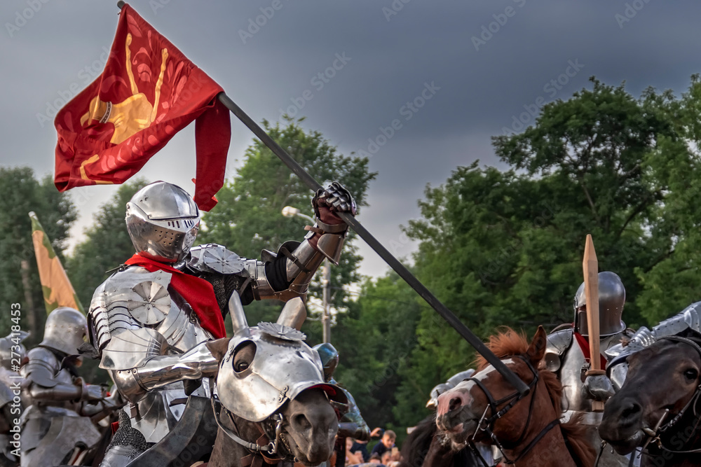 Naklejka premium Knight on horseback in medieval steel armor with flag in battle.