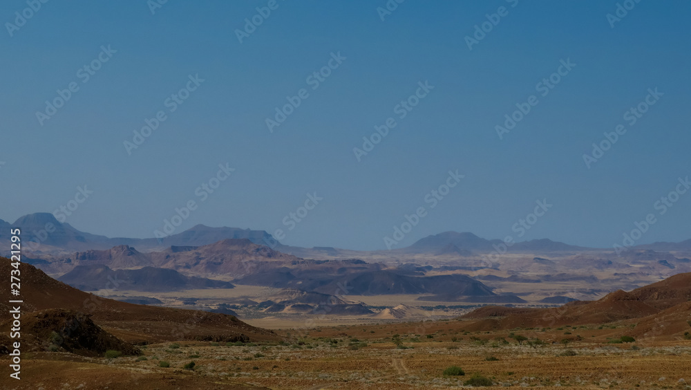 Namibian desert mountains with brown and yellow rock, ostrich in the foreground, dry desolate landscape Namibian desert mountains with brown and yellow rock, ostrich in the foreground, dry desolate landscape
