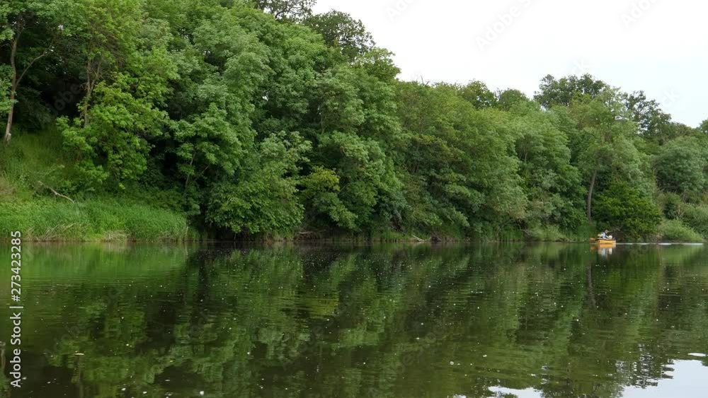 Paddling downstream the river in summer, small motorboat approaching in a distance. Low angle view from kayak or canoe. Paddling downstream the river in summer, small motorboat approaching in a distance. Low angle view from kayak or canoe.