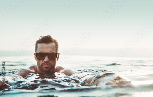 Portrait of a handsome, muscular man relaxing in a warm tropical water photo