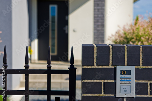 Modern private house doorway withj closed gate and intercom bell.