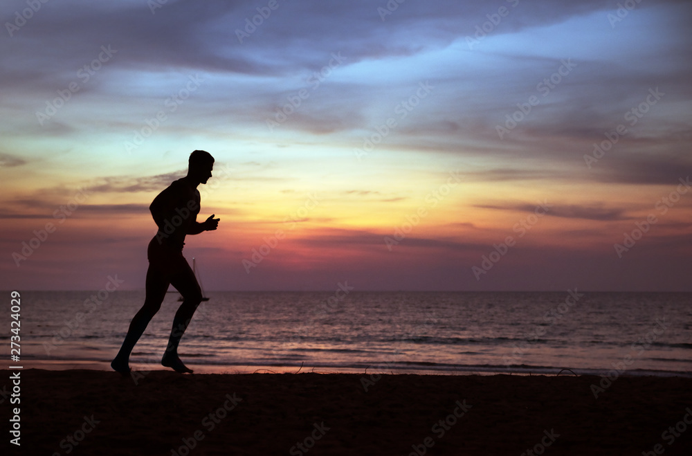 Young, fit man doing jogging on a tropical beach