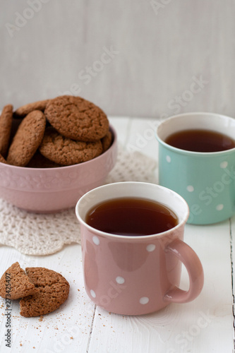 A tasty snack: two cups of tea and a bowl of cookies. © myrka