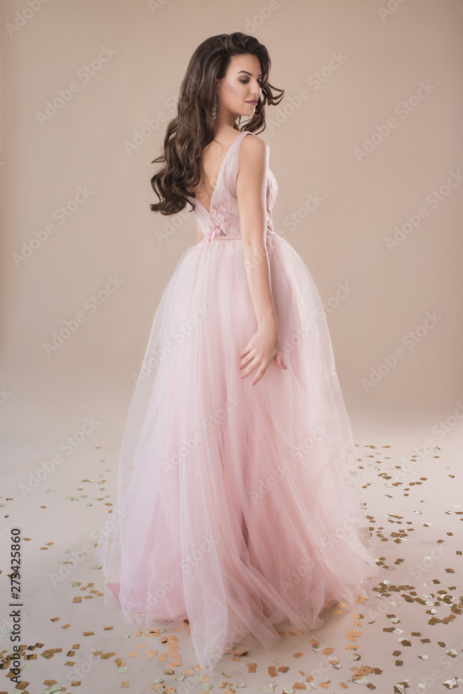 Beautiful girl in evening elegant dress posing on paper beige studio background full length portrait Beautiful girl in evening elegant dress posing on paper beige studio background full length portrait