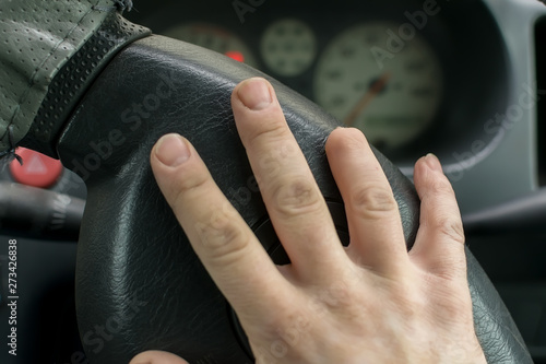 Hand of a man with a missing finger phalanx on the background of the steering wheel and dashboard of the car © Евгений Медведев