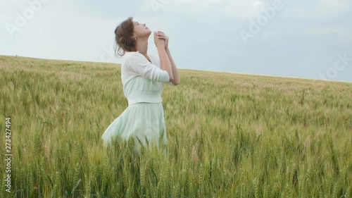 a young girl praying in a wheat field, a woman among ears of corn enjoying nature and thanking God, a concept of religion and faith