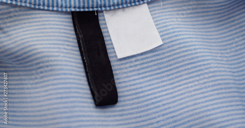 blank black and white clothing label on blue fabric texture background