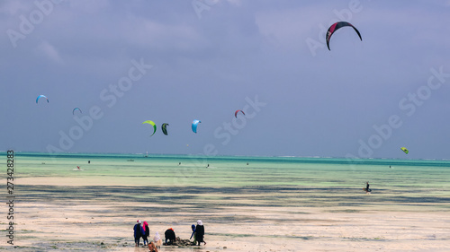 Kite surfing on the beach in Zanzibar over turquoise blue water 