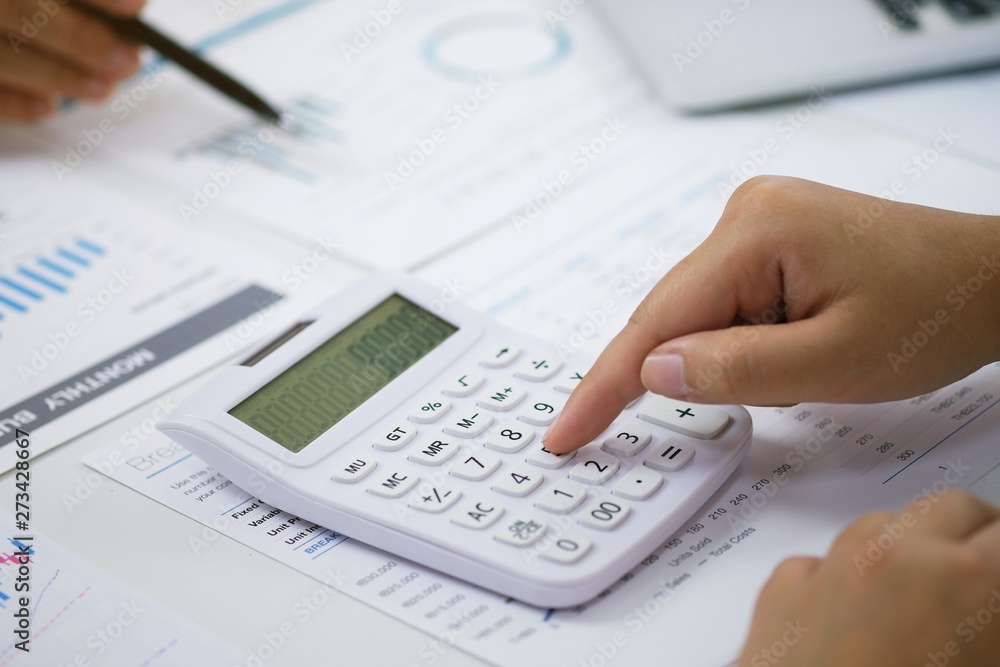 Businessman analyzing investment charts and pressing calculator buttons over documents. Accounting Concept. Businessman analyzing investment charts and pressing calculator buttons over documents. Accounting Concept.