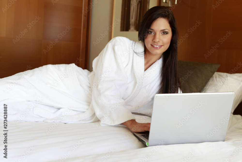 Jeune femme brune en peignoir allongée sur son lit Jeune femme brune en peignoir allongée sur son lit