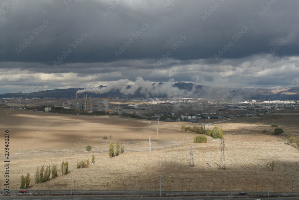 Obraz premium Air pollution created by the smoke coming from the chimney of the cement factory in Turkey's capital city Ankara, cities, mountains and clouds.