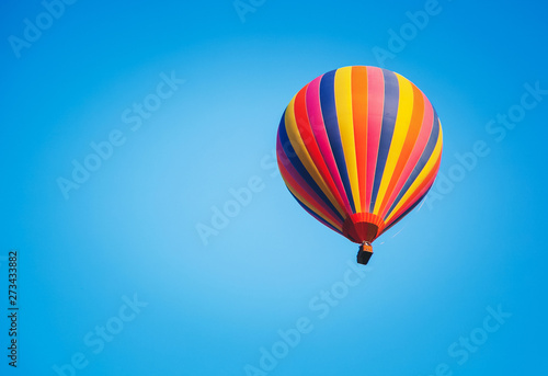 Bright striped multicolored balloon in the blue sky, freedom of travel adventure