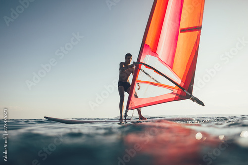 Young windsurfer catch the wind on windsurf board