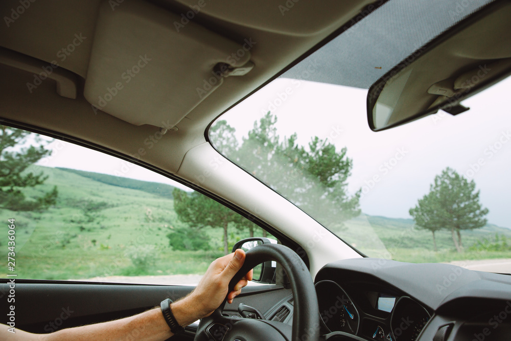 Close up photo of a man driving a car with a picturesque landscape on the background Close up photo of a man driving a car with a picturesque landscape on the background