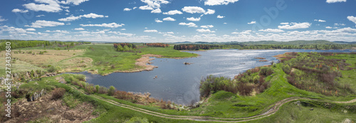Fototapeta Naklejka Na Ścianę i Meble -  Panoramic footage of Russia nature; lake surrounded by birch pine trees, spring green meadows; forest mountains in the background; leaves swaying in the wind; aerial view; drone flying over a river