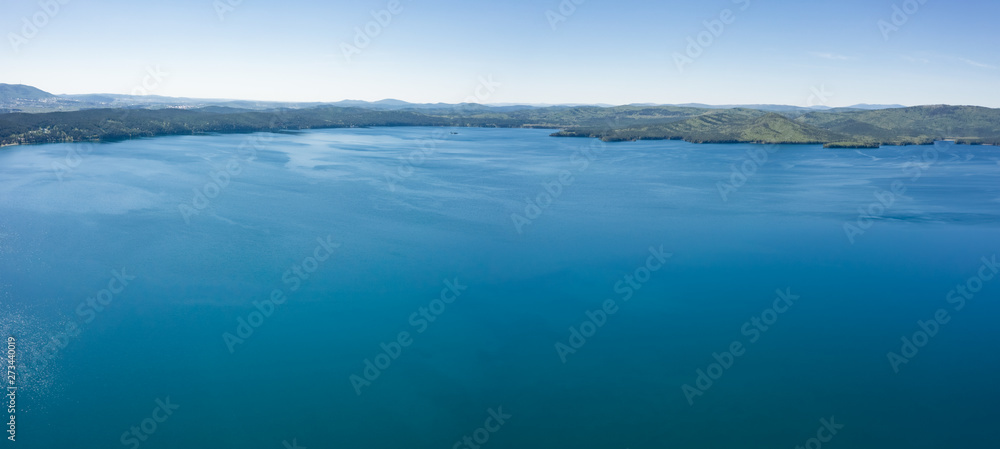 Lake with turquoise water, green trees; montain in the background; reflection in the water; beautiful summer landscape lake surrounded by forest; aerial drone shot over beautiful mountain forest lake