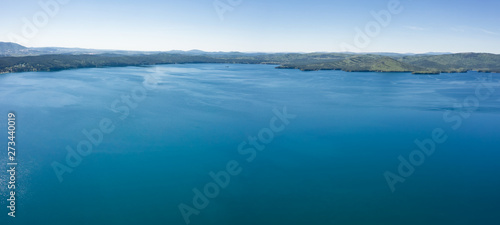 Lake with turquoise water, green trees; montain in the background; reflection in the water; beautiful summer landscape lake surrounded by forest; aerial drone shot over beautiful mountain forest lake