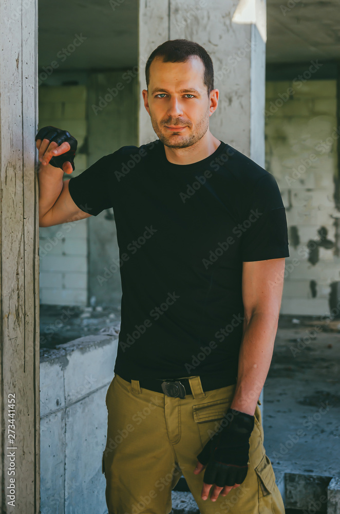 Attractive brutal man in black in an abandoned building. Stalker, lover of extreme adventures. Attractive brutal man in black in an abandoned building. Stalker, lover of extreme adventures.