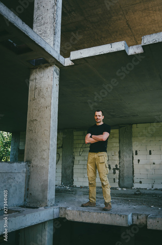 Attractive brutal man in black in an abandoned building. Stalker, lover of extreme adventures. © Alona Dudaieva