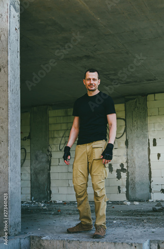 Attractive brutal man in black in an abandoned building. Stalker, lover of extreme adventures. © Alona Dudaieva