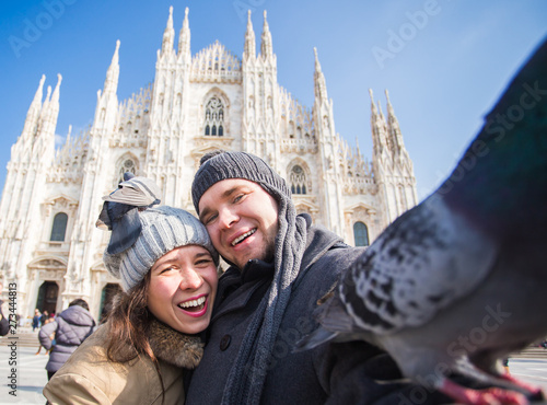 Couple taking self portrait with pigeon in Duomo square in Milan. Winter traveling, Italy and relationship concept