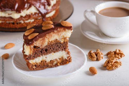 Homemade chocolate cake with milk cream  caramel and almonds on white wooden background. cup of coffee.