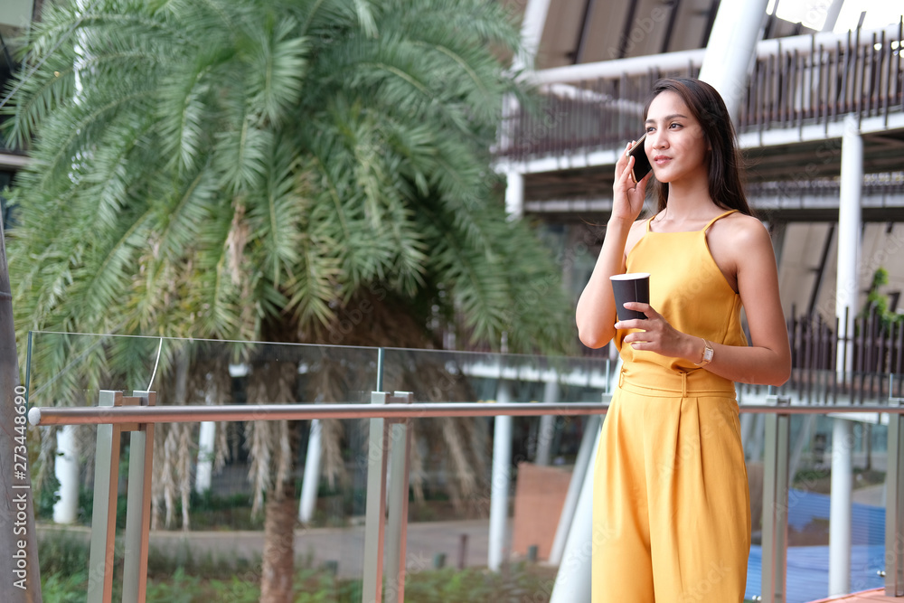 woman holding coffee cup & talking on smart phone outdoor