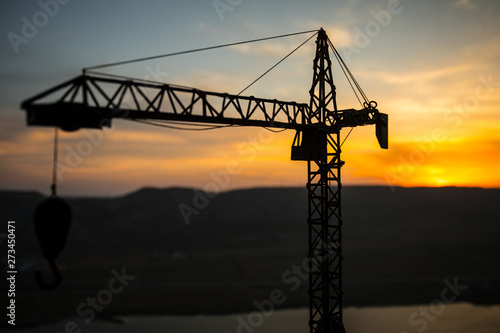 Abstract Industrial background with construction crane silhouette over amazing sunset sky. Tower crane against the evening sky. Industrial skyline