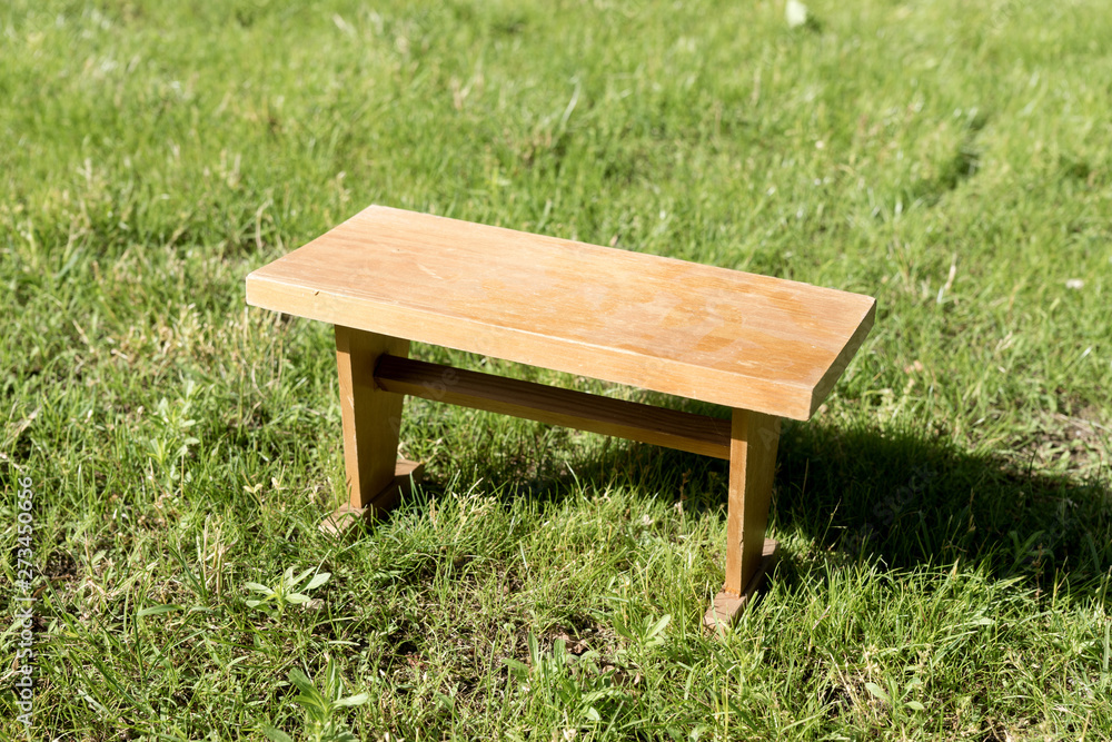 Small angular wooden table on green grass in the garden Small angular wooden table on green grass in the garden