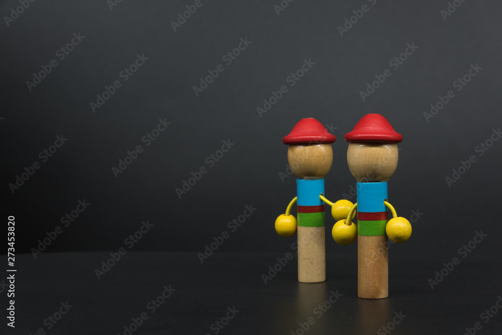 2 colored puppets holding hands standing on the right side of black background