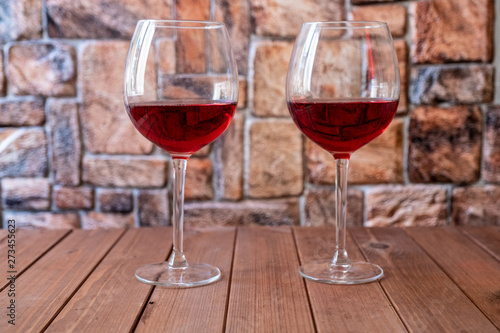 two glasses of red wine on a wooden table