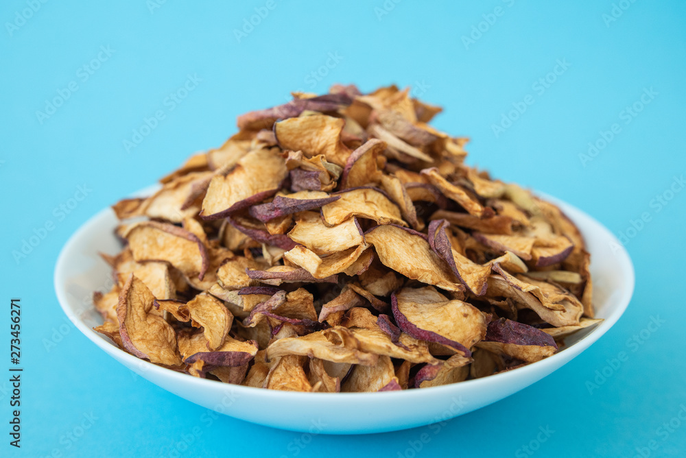 dried apples in white plate on blue background dried apples in white plate on blue background
