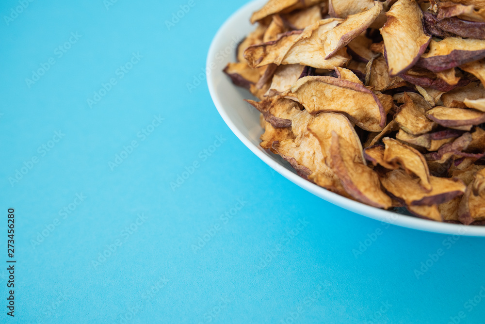 dried apples in white plate on blue background dried apples in white plate on blue background