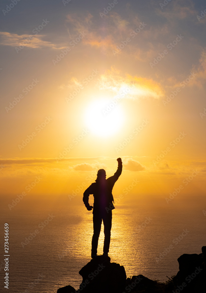 silhouette achievements successful arm up man is on top of hill celebrating success with sunrise over the sea, Basque Country, Spain