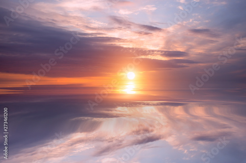 Sunset on the sky, bright sun and colorful clouds over the calm sea.