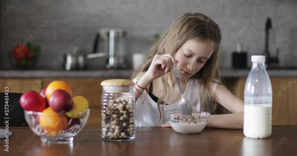 A sad child without appetite sitting at the table in the kitchen. A sad child without appetite sitting at the table in the kitchen.