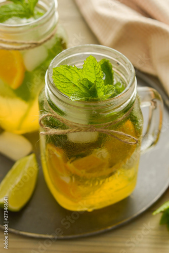 Homemade lemonade with lime, mint in a mason jar on a wooden rustic table. Summer drinks.
