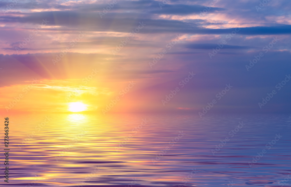 Sunset on the sky, bright sun and colored clouds over the rays against the backdrop of sea waves.