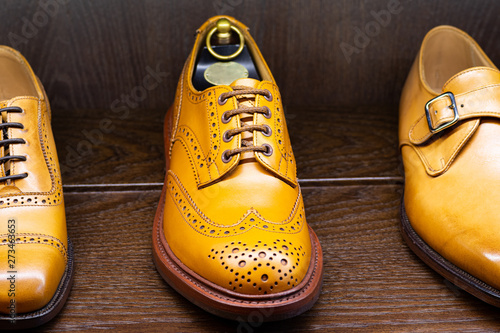 Tan full grain leather brogues shoes set on wooden display in in men shoes boutique store. photo