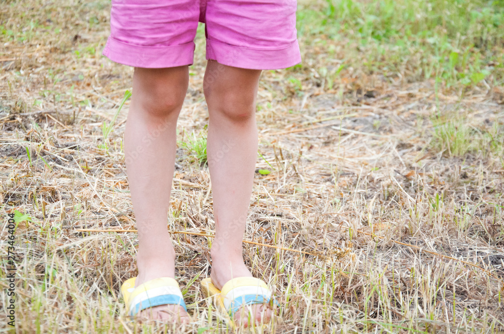 little girl in shorts and flip-flops standing on the mown grass