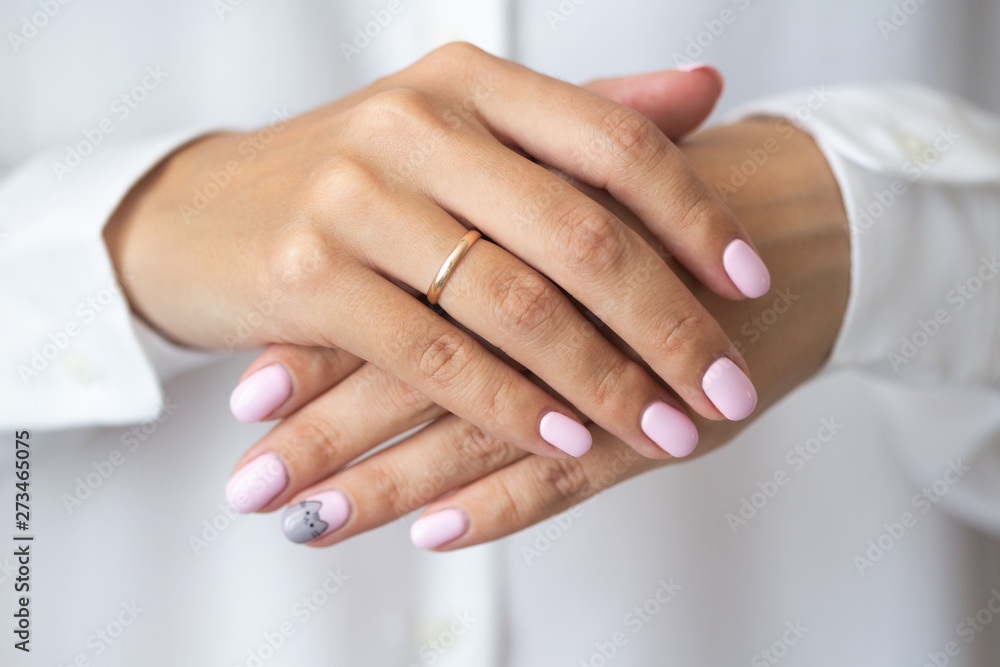 Close-up photo of elegant light pink manicure over white shirt background, tender women's hands with perfect nails, spa and care Close-up photo of elegant light pink manicure over white shirt background, tender women's hands with perfect nails, spa and care