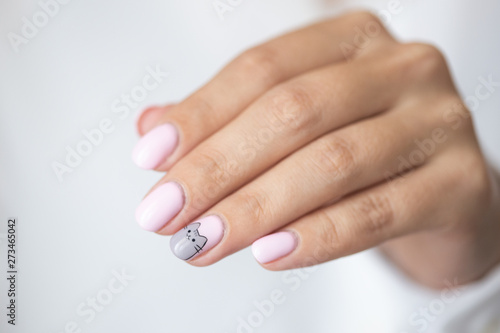 Close-up photo of elegant light pink manicure over white shirt background, tender women's hands with perfect nails, spa and care