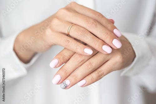 Close-up photo of elegant light pink manicure over white shirt background  tender women s hands with perfect nails  spa and care